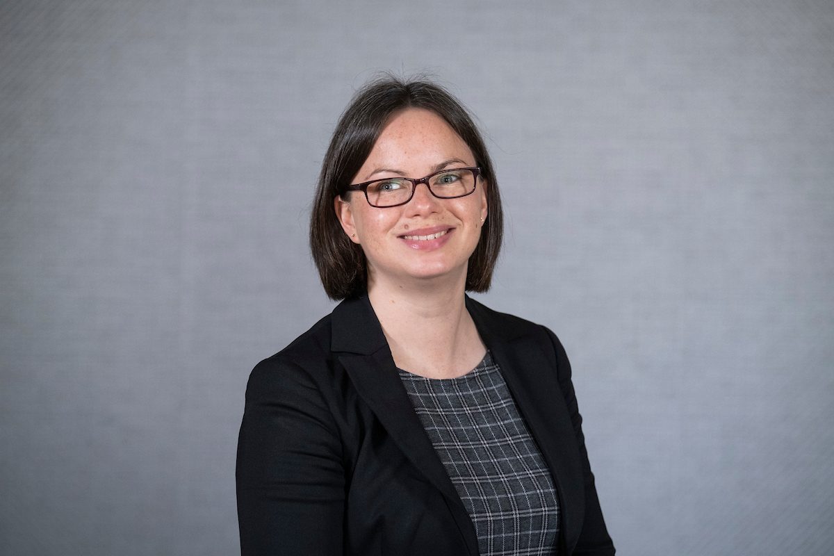 Woman with glasses in black blazer smiling for portrait