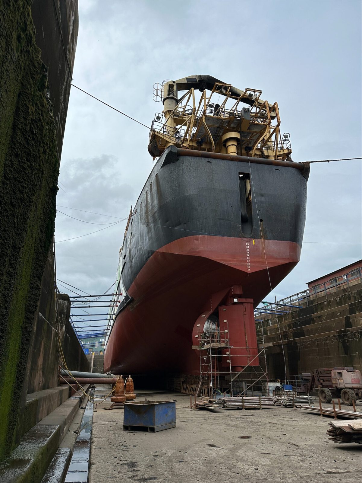 Large vessel in dry dock undergoing maintenance at shipyard facility