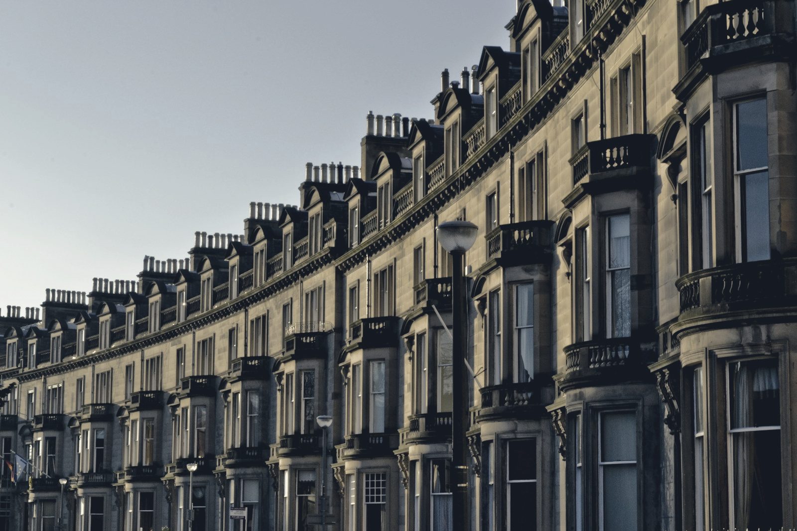 Curved row of Georgian sandstone terraced buildings with chimneys under a clear blue sky