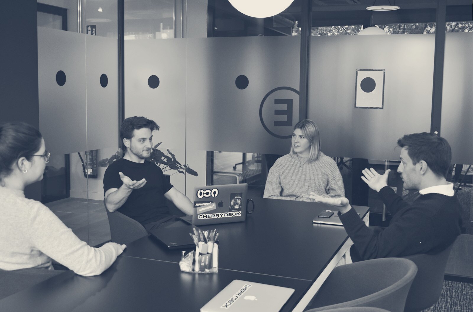 Four people in a meeting around a black table in a modern office